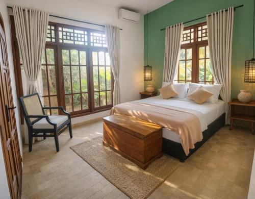 a bedroom with a bed and a chair and windows at Villa Andia in Gili Islands