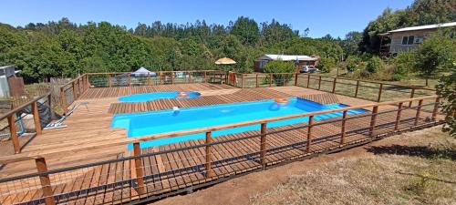 een houten terras met een zwembad erop bij Cabañas y Agroturismo El Trolofken in Pocuno