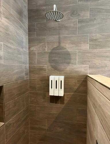 a bathroom with a shower with brown tiles at Lina Élite Suites in Chihuahua