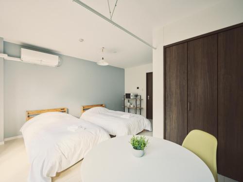 two beds in a room with a table and chairs at vetta Egretta Yatsushiro Free Parking in Yatsushiro