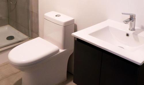 a bathroom with a white toilet and a sink at Hotel Laraquete in Laraquete