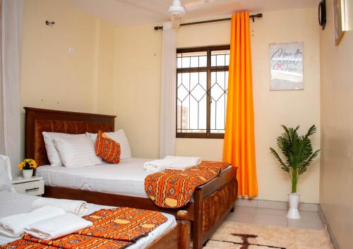 zwei Betten in einem Zimmer mit orangefarbenen Vorhängen und einem Fenster in der Unterkunft Bamburi BnB in Mombasa