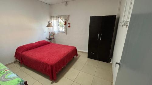 a bedroom with a red bed and a black cabinet at Don Francisco in Junín