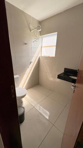 a white bathroom with a toilet and a window at Flat em Carapibus in Conde