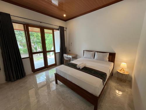 a bedroom with a bed and a large window at Kuta Garden in Kuta Lombok