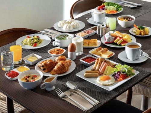 a table with plates of breakfast food on it at Ibis Bangkok Riverside in Bangkok
