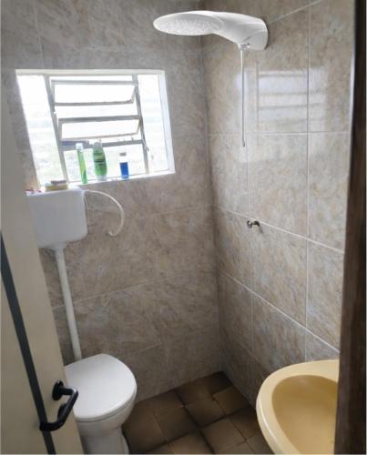a bathroom with a toilet and a sink and a window at Casa para até 6 pessoas, próxima do mar in Cidreira