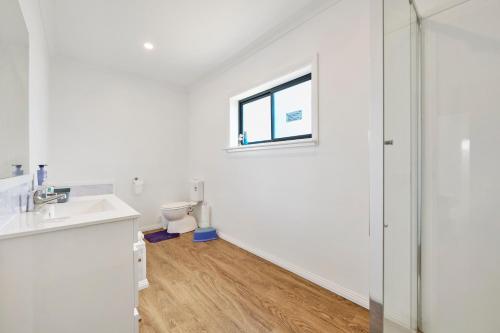 a white bathroom with a toilet and a window at Wheeler's Paradise in Paradise Beach