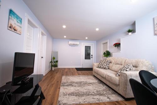 a living room with a couch and a tv at Richie's Place A Cozy 2-BR Apt in Fredericton in Fredericton