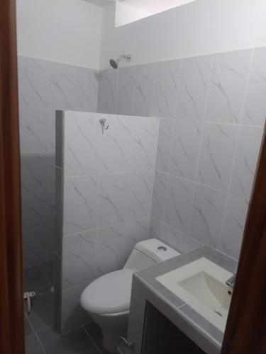 un bagno bianco con un water e un lavandino di Acogedor apartamento a Apartadó