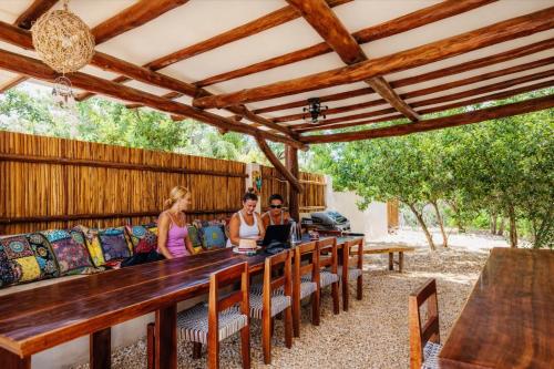 een groep mensen die aan een lange houten tafel zitten bij Island Escape for Groups Hosted by Atenea Holbox in Holbox Island