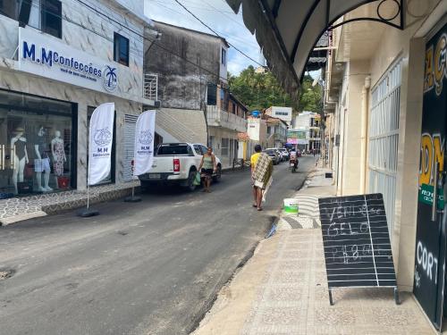 Ein Mann, der eine Straße entlang geht, neben einem Gebäude in der Unterkunft At Suites in Maragogi