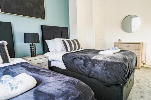 a bedroom with two beds and a mirror at Elm House in Bathgate