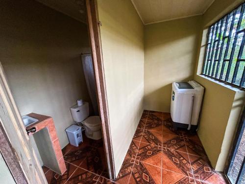 a small bathroom with a toilet and a window at Cabaña La Conquista Naturaleza aves y tranquilidad en Sarapiquí cerca de la Selva in Sarapiquí