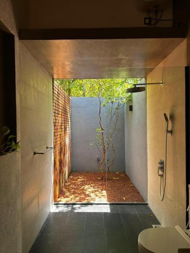 a bathroom with a tree outside of a window at Clover Bentota in Dedduwa