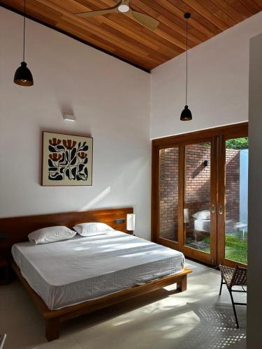 a bedroom with a bed and a large window at Clover Bentota in Dedduwa