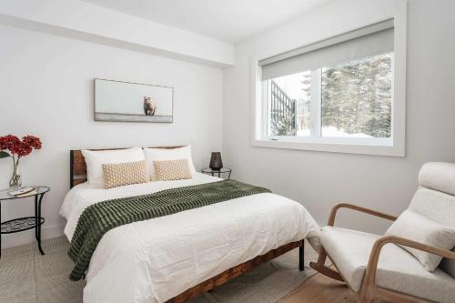 een witte slaapkamer met een bed en een stoel bij Mont Blanc 121-111 in Saint-Faustin