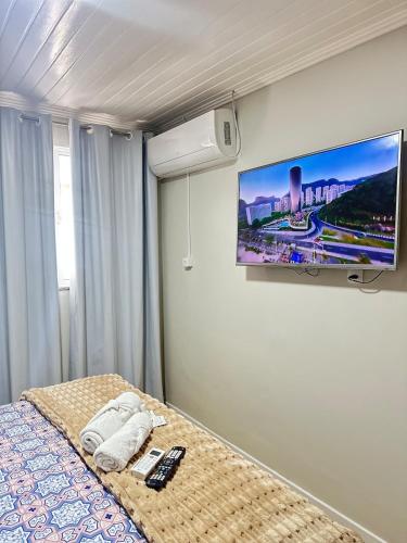 a bedroom with a bed with a tv on the wall at Suíte Quarto 3km de Florianópolis in São José