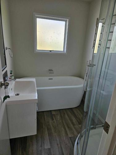 a bathroom with a tub and a sink and a window at Podgsters in Mangonui