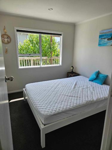 a bedroom with a white bed with a window at Podgsters in Mangonui