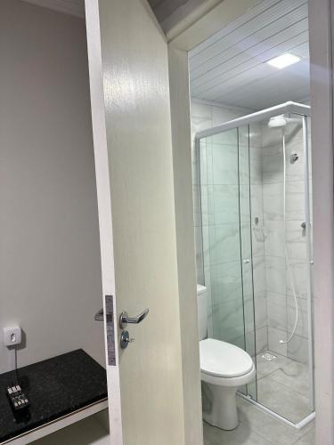 a bathroom with a toilet and a glass shower at Suíte Quarto 3km de Florianópolis in São José