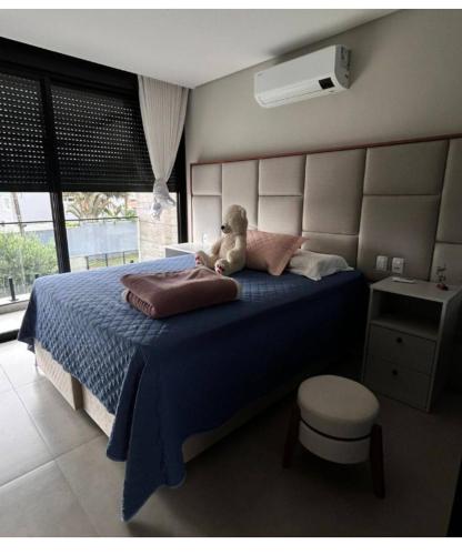 a teddy bear sitting on a bed in a bedroom at Casa de luxo com piscina in Florianópolis