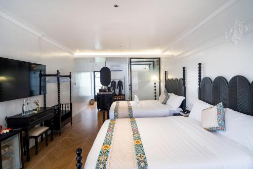 a bedroom with two beds and a desk and a mirror at Madeline Paradise Resort in Panglao