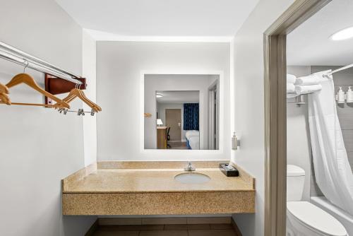 a bathroom with a sink and a toilet and a mirror at Days Inn by Wyndham Chesapeake in Chesapeake