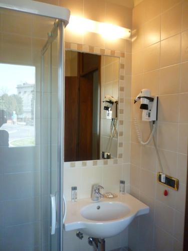 a bathroom with a sink and a shower with a mirror at Hotel Quo Vadis in Udine