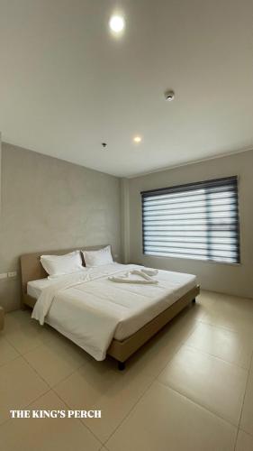a bedroom with a large white bed with a window at The Perch Hostel in Olongapo