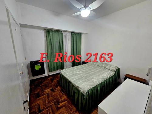 a bedroom with a bed with a green comforter and a window at Dos ambientes plaza colon in Mar del Plata