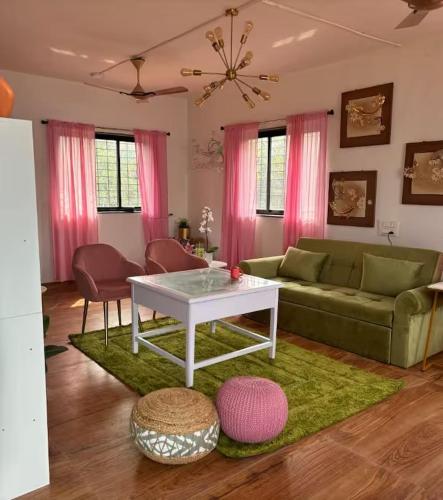 a living room with a green couch and pink curtains at Sandbox in Malvan