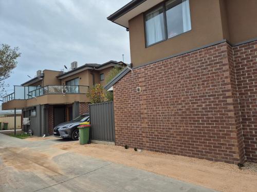 een bakstenen gebouw met een auto op een oprit bij Sredna Homestay in Braybrook