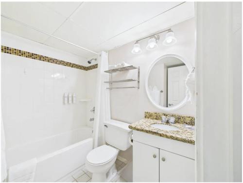 a white bathroom with a toilet and a sink at Galveston condo- walk to beach - ocean view - 2 pools in Galveston