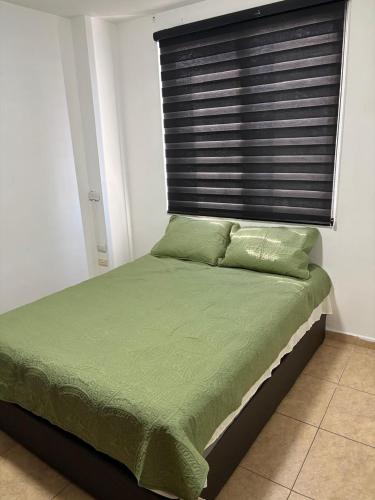 a bed with a green comforter and a window at Departamento Torres del Rio Privada Desarrollo Urbano Tres Rios Facturamos in Culiacán