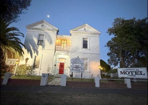 a white building with a sign in front of it at Campbell st Lodge in Castlemaine