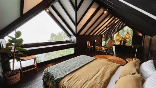 a bedroom with a bed in a room with large windows at Wanagiri Cabin Wanara in Gitgit