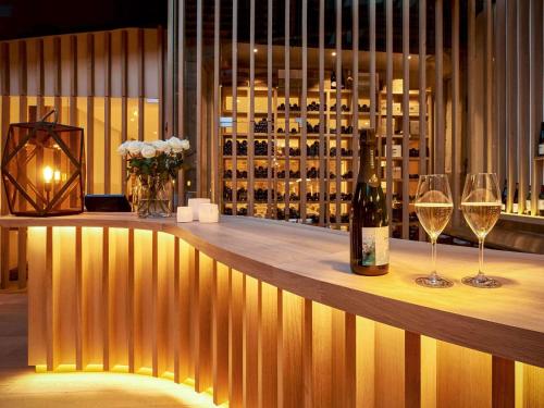 een bar met 2 wijnglazen en een fles wijn bij 5 Terres Hotel & Spa - MGallery Collection in Barr