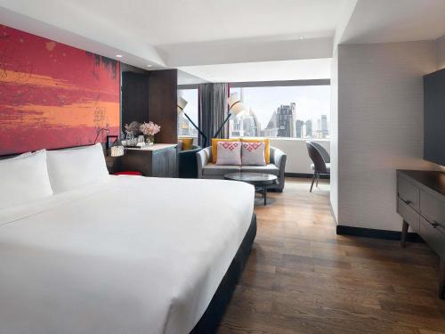 a hotel room with a large bed and a living room at Mercure Bangkok Sukhumvit 11 in Bangkok
