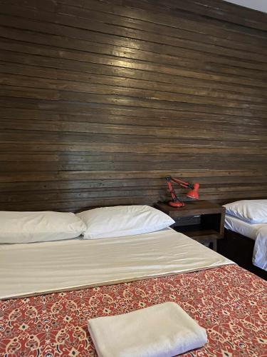 two beds in a room with a wooden wall at Baluarte Rest and Relaxation in Sampong