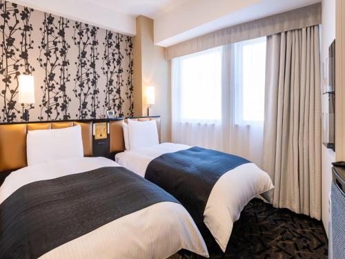due letti in una stanza d'albergo con finestra di APA Hotel Toyama Ekimae a Toyama