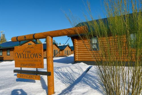 a sign in the snow in front of a log cabin at The Willows Cabins in West Yellowstone