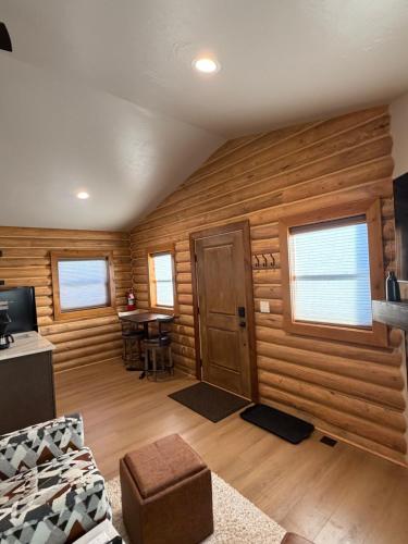 a living room with wooden walls and a door at The Willows Cabins in West Yellowstone
