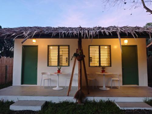 a house with two tables and a thatched roof at Garden Village in El Nido