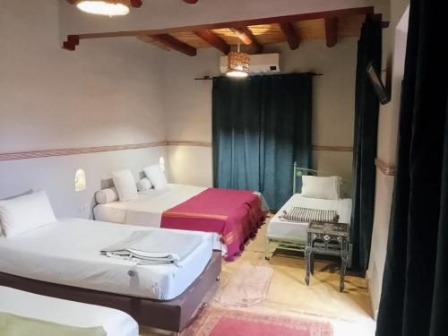 een kamer met twee bedden en een tafel erin bij dar boumida in Lalla Takerkoust