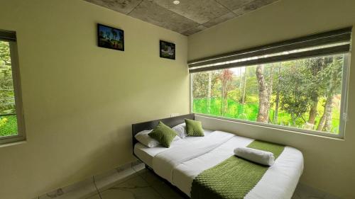 a bed in a room with a large window at Ayurnest Pool Resort Wayanad in Batheri