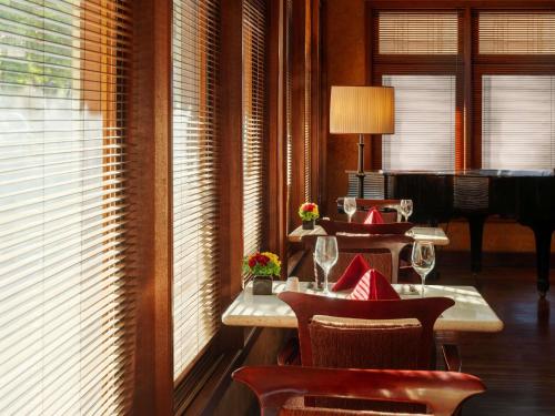 een restaurant met 2 tafels en stoelen en een piano bij Hotel Majapahit Surabaya MGallery in Surabaya