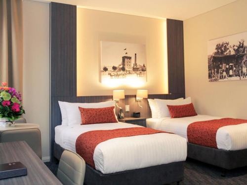 ein Hotelzimmer mit zwei Betten und einem Tisch in der Unterkunft Mercure Orange in Orange