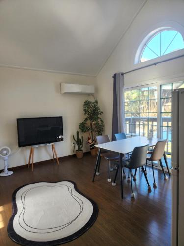 un soggiorno con un tavolo e una tv di Honey Bear Pension a Pyeongchang