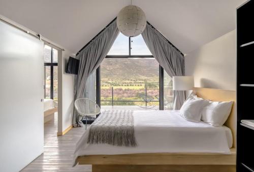 a bedroom with a large bed and a large window at OENO WINE LODGE Valle de Guadalupe in Valle de Guadalupe